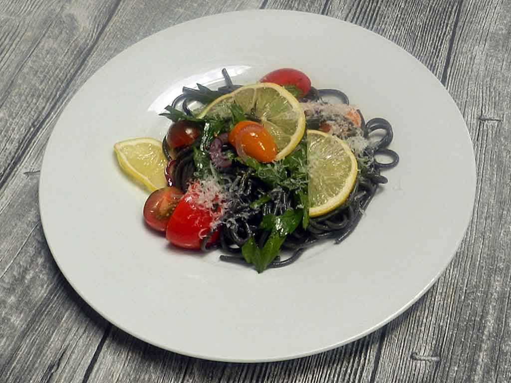 Schwarze Spaghetti mit bunten Tomaten.