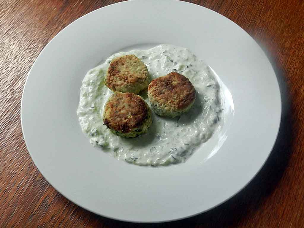 Zucchini-Feta-Bouletten auf angemachtem Joghurt.